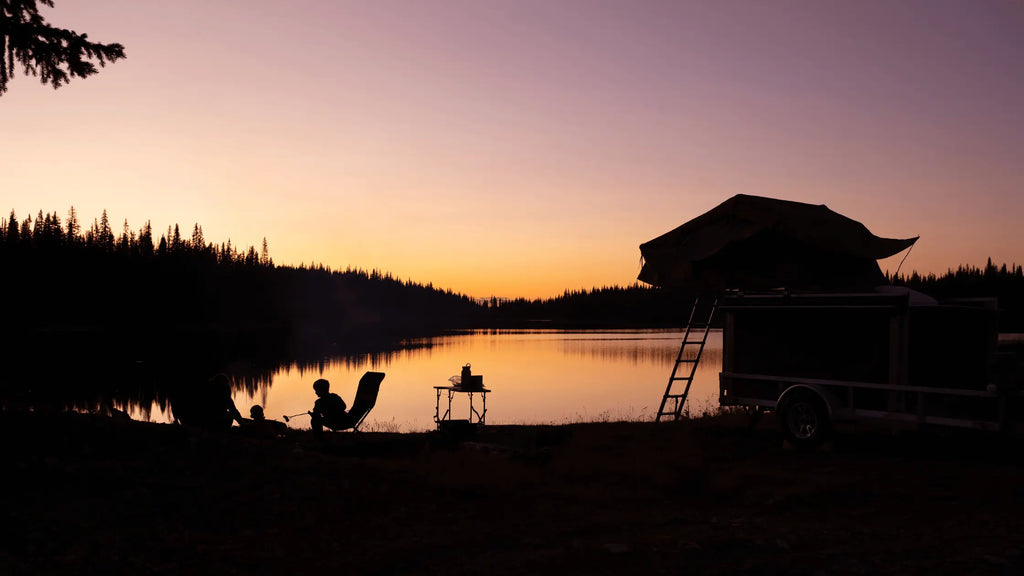 Rooftop tent setup by a lake with sunset backdrop, ideal for camping enthusiasts exploring benefits over traditional caravans and tents.
