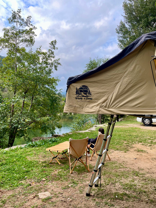 louer materiel camping table chaise montpellier location herault 34000 woodys camp Table de camping en bois pliable installée en extérieur avec des chaises, des boissons et de la nourriture, mettant en avant un design durable pour des repas confortables en plein air.