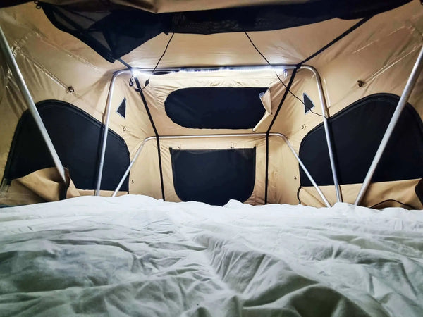 Intérieur d'une tente de toit avec un éclairage LED flexible pour le camping, mettant en avant la portabilité et l'illumination.