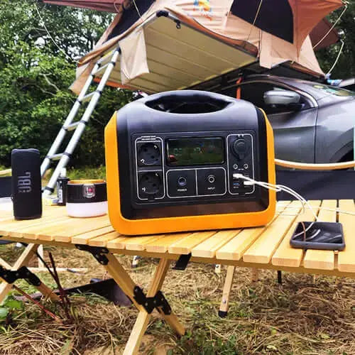 Kit de batterie portable avec une capacité de 1200WH et des panneaux solaires sur une table de camping, idéal pour les voyages et les aventures en plein air.